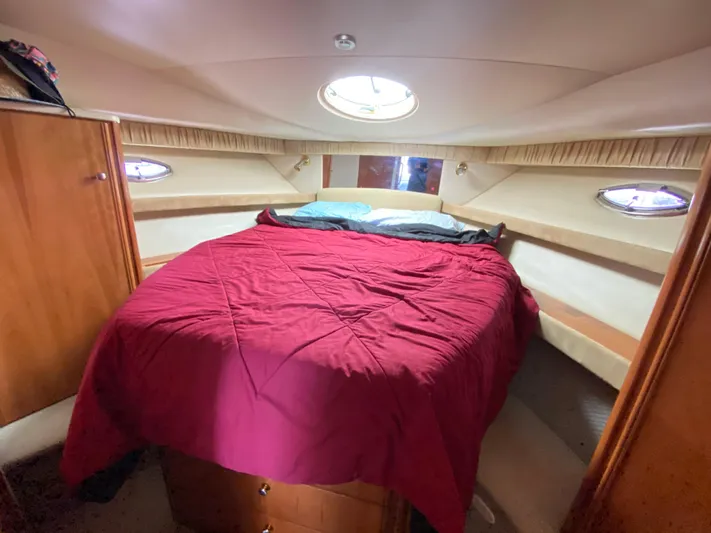  Yacht Photos Pics Cozy bedroom in 2004 Meridian 381 Sedan yacht with red bedding and porthole windows.