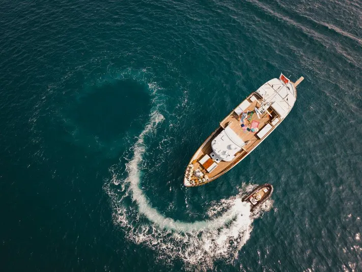 Yona Yacht Photos Pics Aerial view of 1981 Vripack Doggersbank 20 yacht with a small boat on blue ocean.