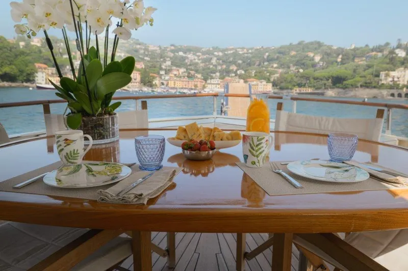 Yona Yacht Photos Pics Elegant dining setup on Vripack Doggersbank 20 yacht, 1981, with scenic coastal view.