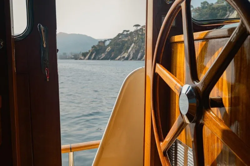 Yona Yacht Photos Pics Wooden steering wheel on 1981 Vripack Doggersbank 20 yacht, overlooking scenic coastal view.