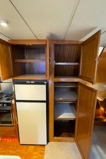 Wind Star Yacht Photos Pics 1993 Ocean Alexander 520 Pilothouse kitchen with open wooden cabinets and a refrigerator.