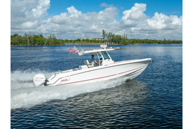 New Seakeeper- 110 Engine Hours- Obo Yacht Photos Pics 2017 Boston Whaler 330 Outrage cruising on a scenic waterway under a blue sky.