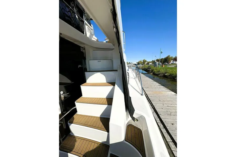  Yacht Photos Pics 2008 Sea Ray 47 Sedan Bridge yacht with wooden steps, docked by a serene waterfront.