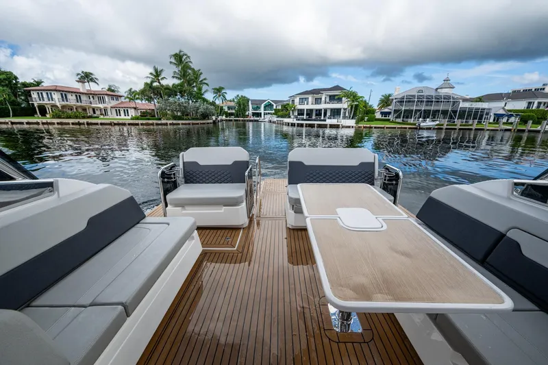  Yacht Photos Pics 2023 Aquila 32 Power Cat interior with elegant seating and table, overlooking waterfront homes.