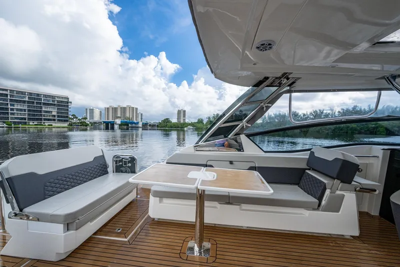  Yacht Photos Pics 2023 Aquila 32 Power Cat interior with seating and table, overlooking waterfront cityscape.