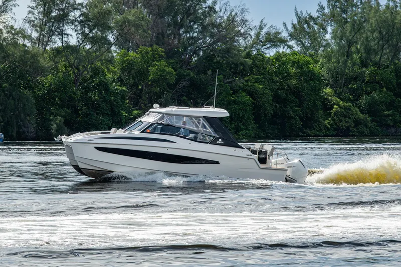  Yacht Photos Pics 2023 Aquila 32 Power Cat cruising on a scenic river with lush greenery.
