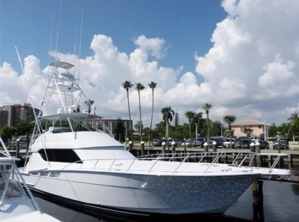 Aguamala Yacht Photos Pics 1998 Hatteras Sportfish yacht docked under a bright blue sky with palm trees.