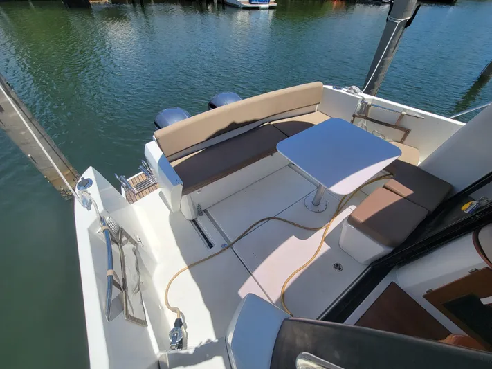 Supervielle Yacht Photos Pics 2016 Jeanneau Merry Fisher 855 boat deck with seating and table, docked on calm water.