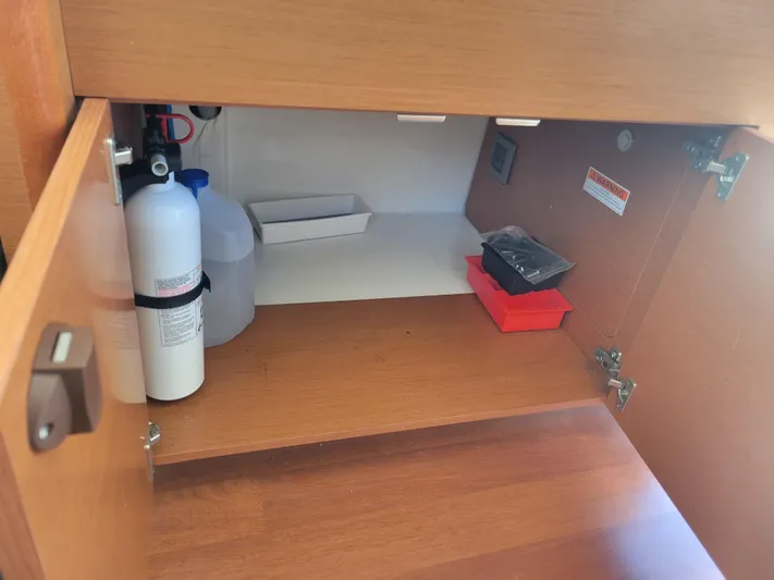 Supervielle Yacht Photos Pics Open cabinet on Jeanneau Merry Fisher 855 boat, showing storage items and fire extinguisher.
