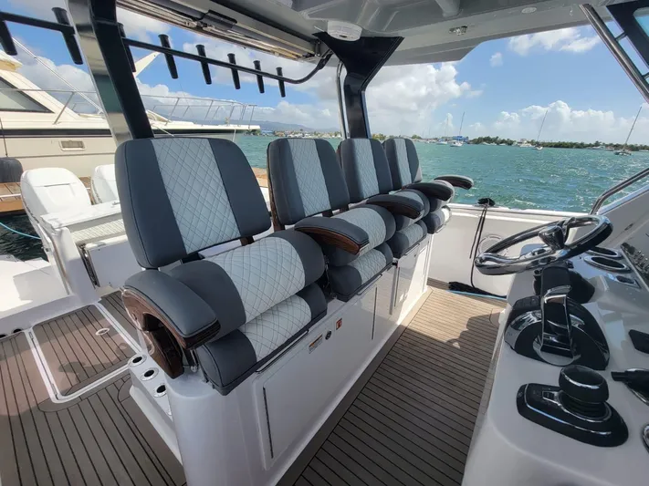  Yacht Photos Pics 2022 Bertram 39 CC boat interior with luxurious seating and steering wheel, docked by the water.