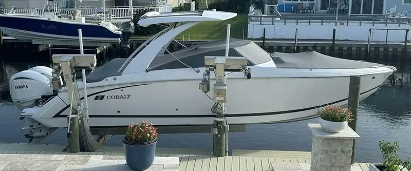  Yacht Photos Pics 2024 Cobalt 30SC Outboard boat docked, covered, with Yamaha engines, in a serene waterfront setting.