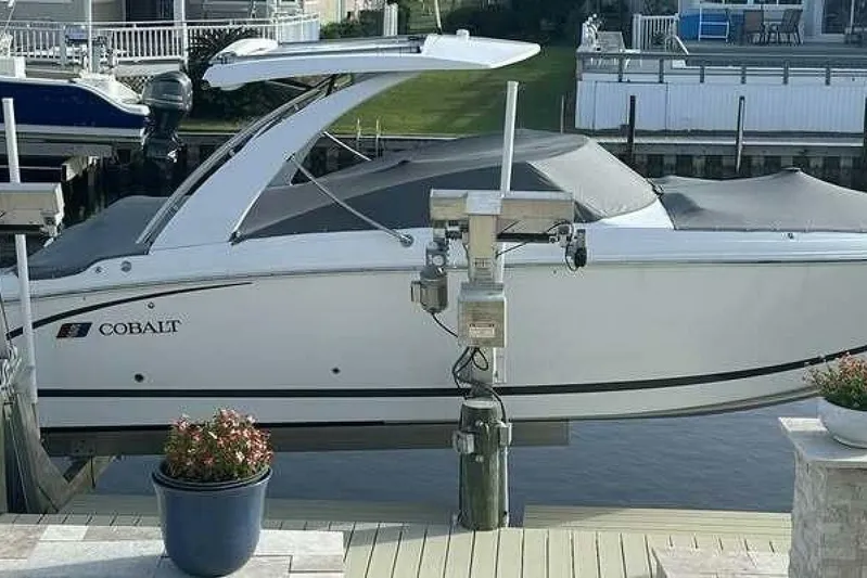  Yacht Photos Pics 2024 Cobalt 30SC Outboard boat docked, covered, with waterfront background.