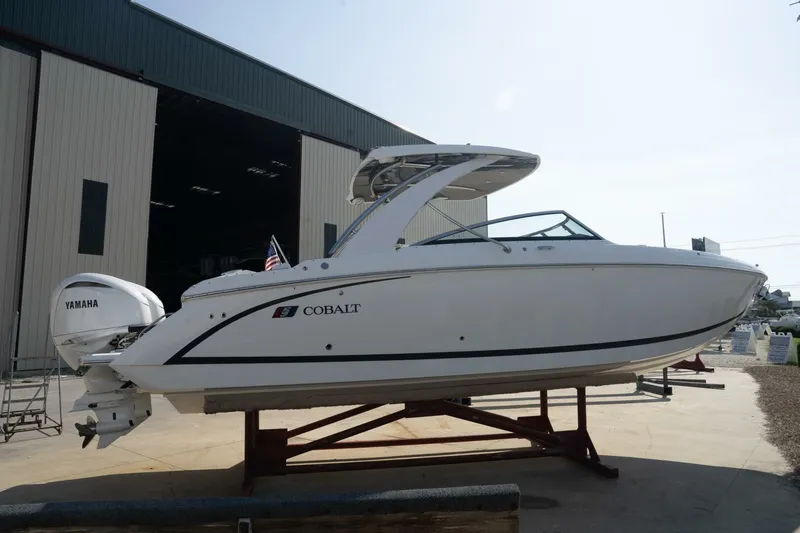  Yacht Photos Pics 2024 Cobalt 30SC Outboard boat with Yamaha engine, displayed outside a large warehouse.