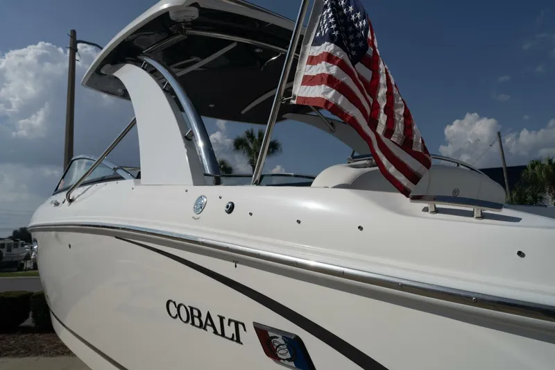  Yacht Photos Pics 2024 Cobalt 30SC Outboard boat with American flag, sleek design under blue sky.