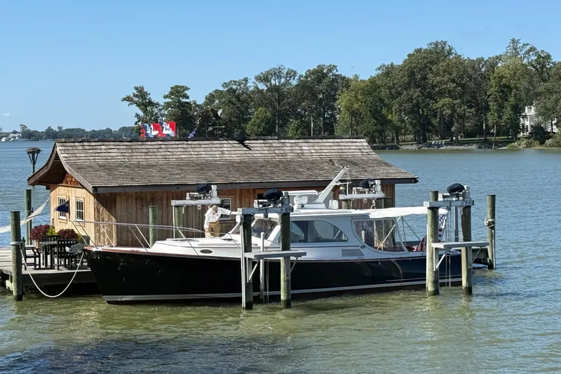 Brass Ring Yacht Photos Pics 2003 Hinckley Talaria 40 docked by a rustic boathouse on a serene lake.