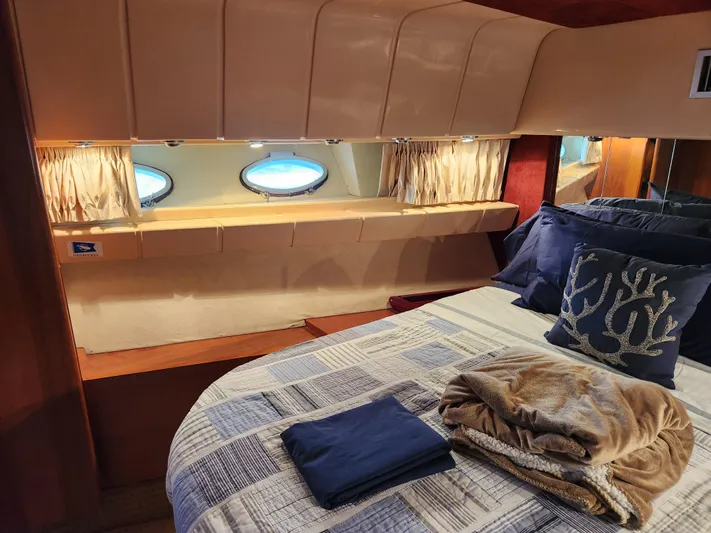 Glorious Quest Yacht Photos Pics Cozy bedroom interior of 1987 Posillipo Technema 52 yacht with porthole windows and nautical decor.