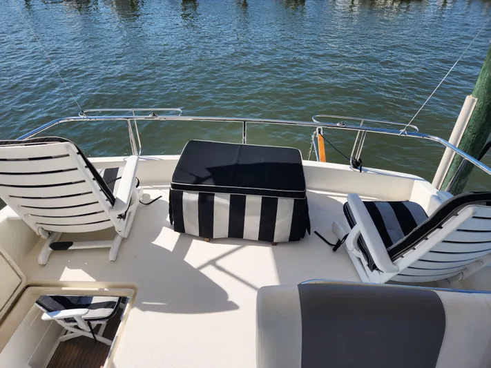 Glorious Quest Yacht Photos Pics Posillipo Technema 52 yacht deck with striped seating, 1987 model, overlooking water.