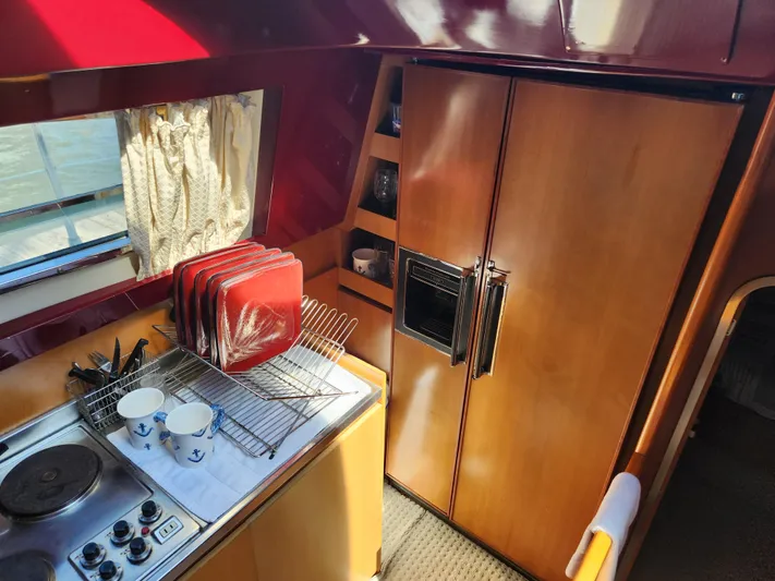 Glorious Quest Yacht Photos Pics Interior of 1987 Posillipo Technema 52 yacht kitchen with stove, dishes, and wooden cabinets.