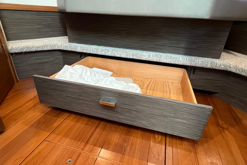 Lady Linn Yacht Photos Pics Open storage drawer in 2020 Tiara Yachts C44 Coupe, featuring wood finish and bedding.