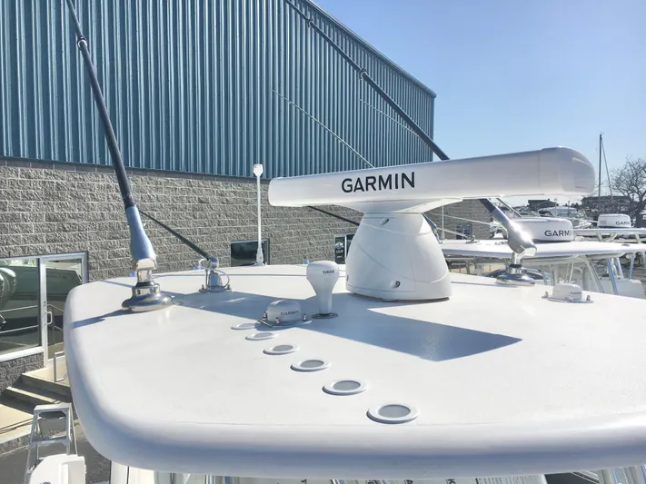  Yacht Photos Pics 2024 Contender 32 ST boat with Garmin radar, docked near a blue warehouse.