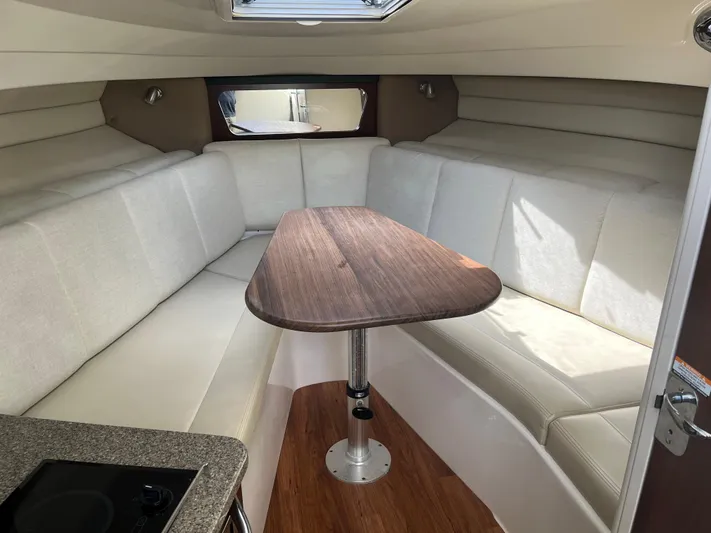  Yacht Photos Pics Interior of 2015 Robalo R305 Walkaround with cushioned seating and wooden table.
