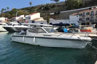 2023 Nimbus W9 boat docked in a scenic marina with hillside and buildings.