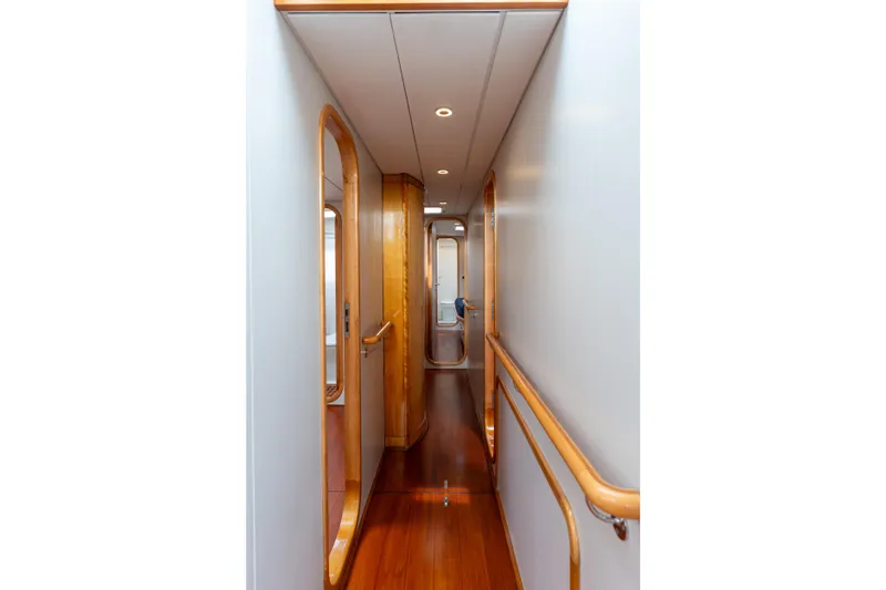 Django Too Yacht Photos Pics Narrow wooden hallway inside 1991 Trehard SLOOP 83 yacht, featuring elegant design.