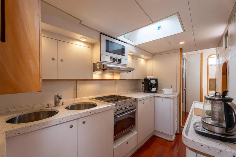 Django Too Yacht Photos Pics Modern kitchen interior on 1991 Trehard SLOOP 83 yacht, featuring sleek appliances and wood accents.