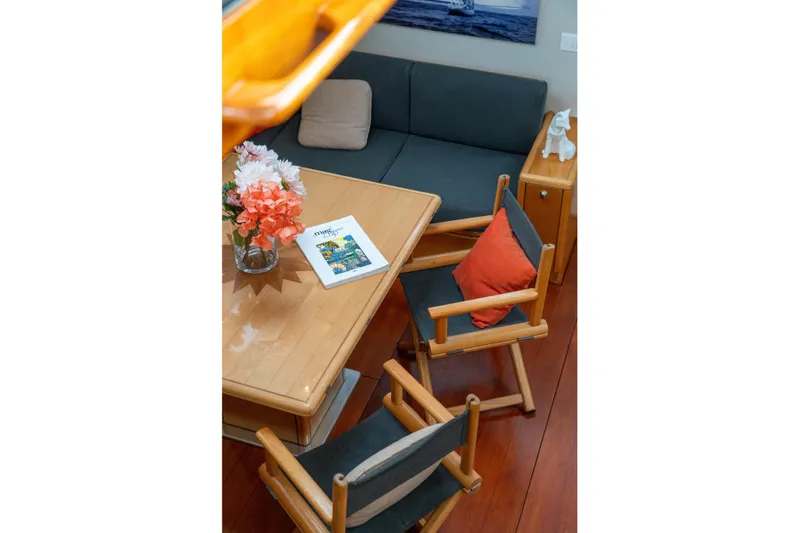 Django Too Yacht Photos Pics Cozy interior of 1991 Trehard SLOOP 83 yacht with wooden furniture and floral decor.