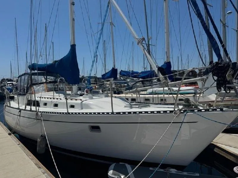 Sailboat docked at marina, Custom SEA MAID model, 1989, with blue covers and clear sky.