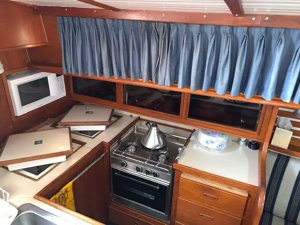 1989 Custom SEA MAID boat kitchen with stove, microwave, and blue curtains.