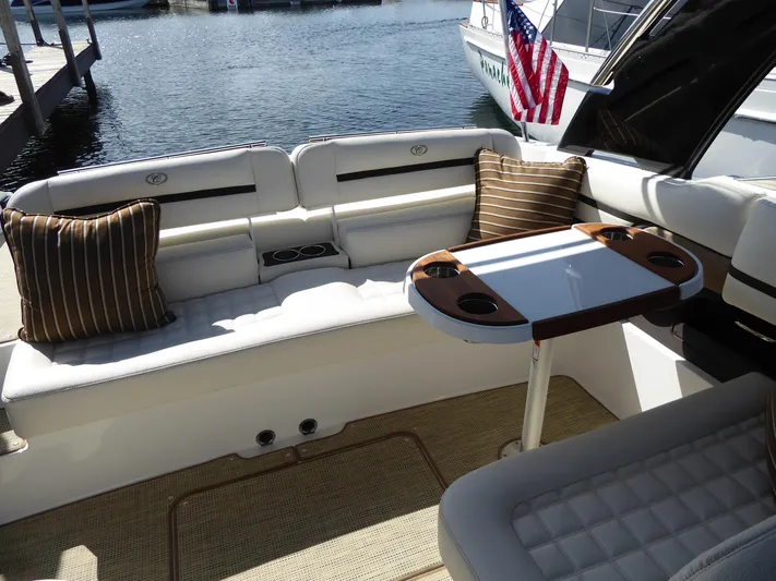  Yacht Photos Pics 2017 Cobalt R30 boat interior with seating, table, and American flag in marina setting.