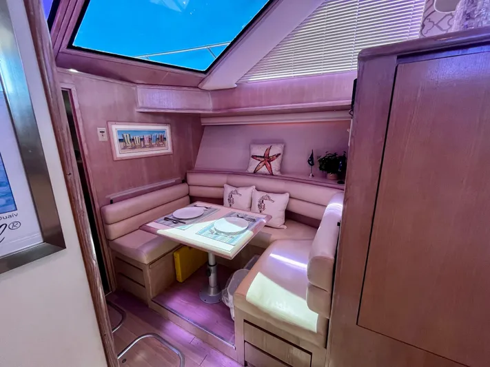 Charlie's Angels Yacht Photos Pics Luxurious 1991 Hatteras 52 Cockpit Motoryacht interior with cozy dining area and skylight.