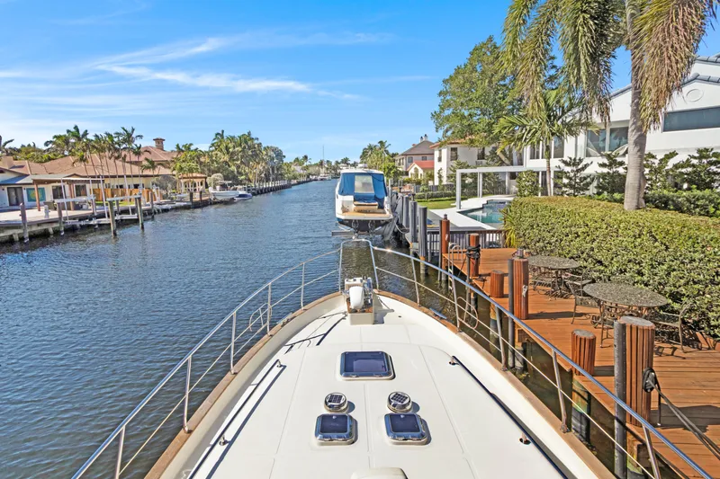  Yacht Photos Pics Luxury yacht cruising through a scenic canal, surrounded by waterfront homes and palm trees.