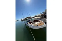 2008 Rinker 228 DB boat docked in a sunny marina, surrounded by other vessels.