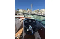 2008 Rinker 228 DB boat dashboard with steering wheel, docked in a marina under clear blue sky.