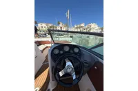 2008 Rinker 228 DB boat dashboard with steering wheel, docked in a sunny marina.