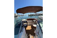 2008 Rinker 228 DB boat interior with canopy, docked in a marina under clear blue sky.