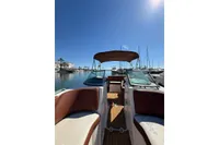 2008 Rinker 228 DB boat docked in a sunny marina, featuring brown seating and canopy.