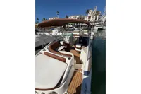 2008 Rinker 228 DB boat with brown seating, docked in a marina under clear blue skies.