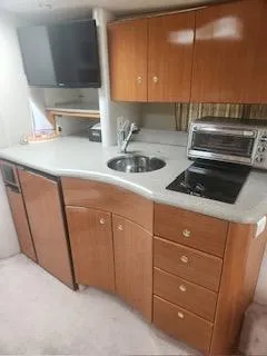 Four-some Fun Yacht Photos Pics 2001 Formula 40 PC yacht kitchen with wooden cabinets, sink, stove, and microwave.