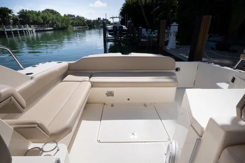  Yacht Photos Pics 2014 Pursuit SC 365i Sport Coupe boat interior with beige seating, docked by a serene waterway.