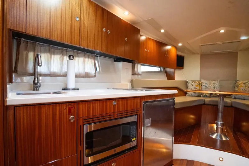  Yacht Photos Pics 2014 Pursuit SC 365i Sport Coupe interior with wood cabinetry, kitchenette, and seating area.