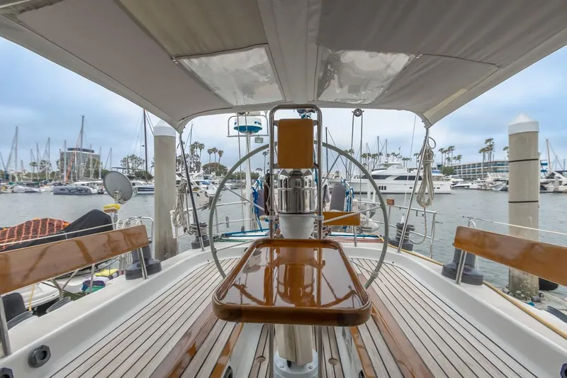 Jano Yacht Photos Pics Farr 55 sailboat cockpit, 1994 model, docked in a marina with wooden seating and steering wheel.