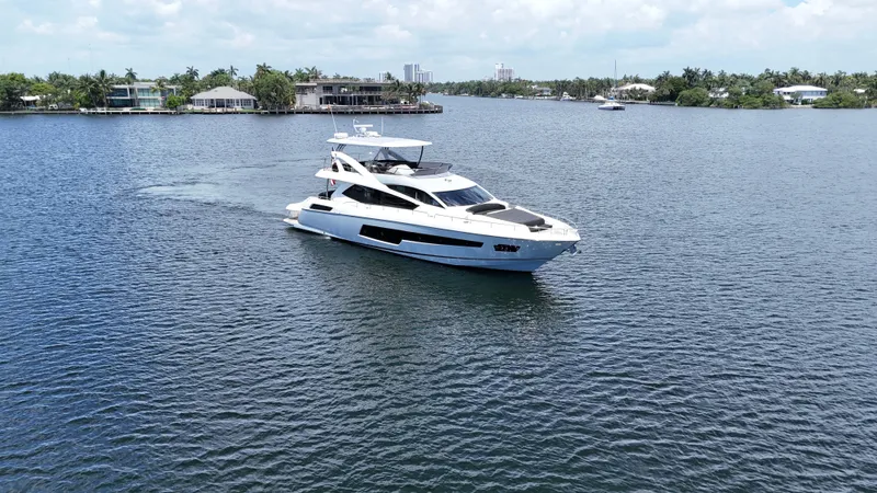 Dirty Dawg Yacht Photos Pics 2017 Sunseeker 75 Yacht cruising on a serene waterway with lush surroundings.