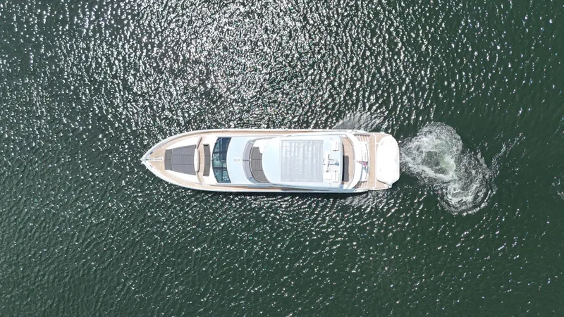 Dirty Dawg Yacht Photos Pics Aerial view of 2017 Sunseeker 75 Yacht cruising on shimmering water.
