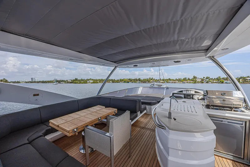 Dirty Dawg Yacht Photos Pics Luxurious 2017 Sunseeker 75 Yacht deck with seating, table, and grill, overlooking serene waters.