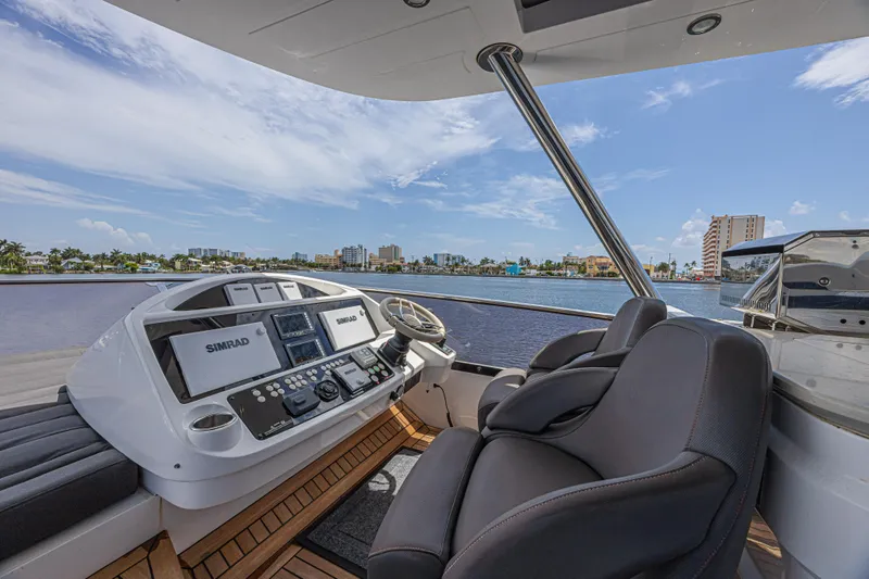 Dirty Dawg Yacht Photos Pics Helm of 2017 Sunseeker 75 Yacht with Simrad navigation, overlooking waterfront cityscape.