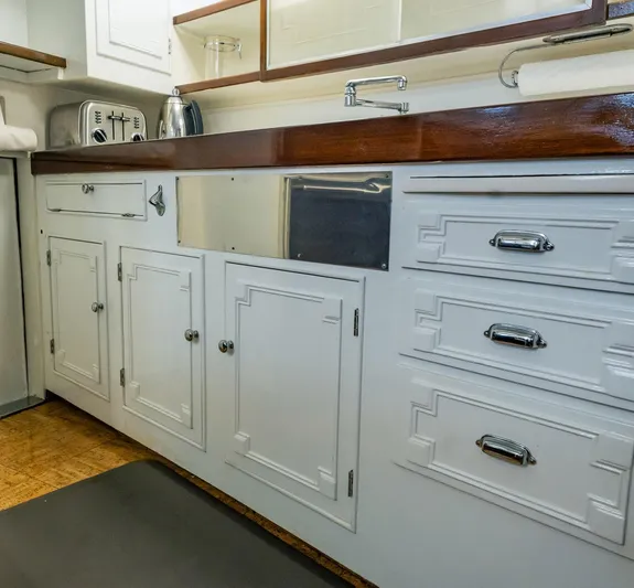 Coconut Yacht Photos Pics White kitchen cabinetry on a 1964 Burger 64' Motor Yacht with wooden countertop.