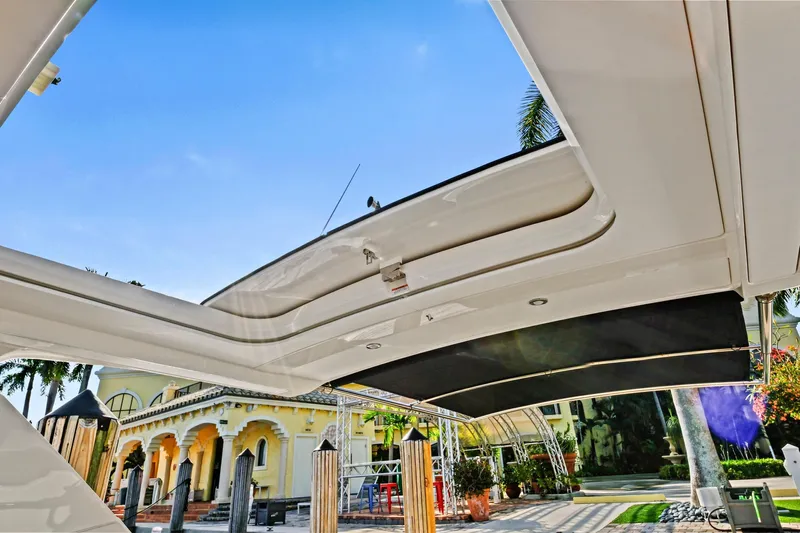 Sensei I Yacht Photos Pics 2021 Sea Ray SLX 400 boat with open sunroof, docked near a luxurious building.